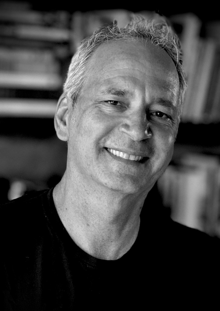 black and white portrait of Phillippe Diederich, smiling and wearing a black t-shirt.